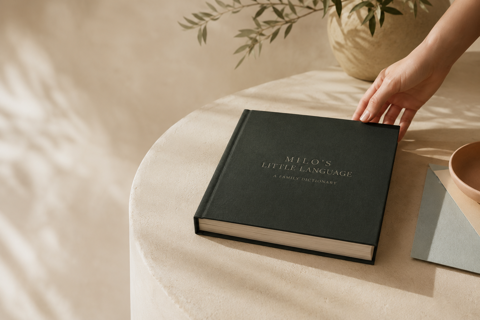 Concept mockup of a personalized forest-green Their Little Language hardcover on a warm ivory plinth